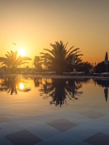 Tramonto su piscina con palme e lettini.