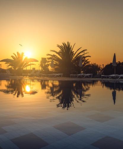 Tramonto su piscina con palme e lettini.