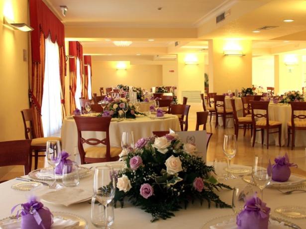 Sala elegante con tavoli apparecchiati, fiori e decorazioni viola.