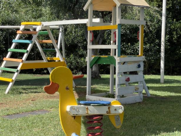 Parco giochi con altalena e dondolo a forma di anatra colorata.