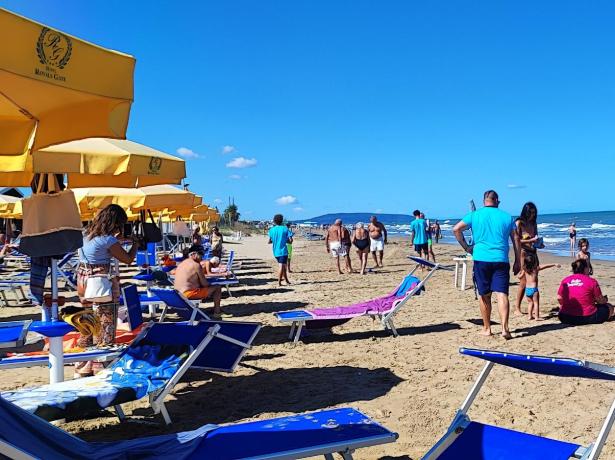 Spiaggia soleggiata con ombrelloni gialli e persone che si rilassano.