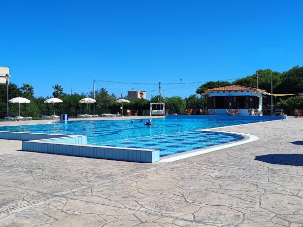 Piscina all'aperto con lettini e ombrelloni in una giornata soleggiata.
