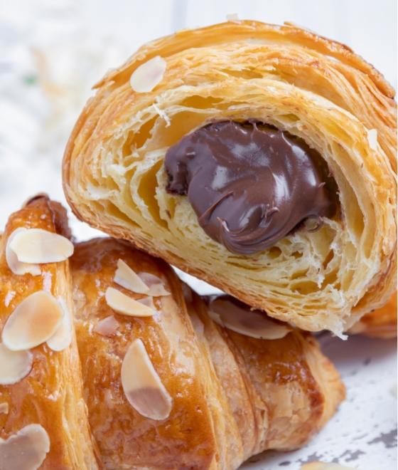 Croissant sfogliato con ripieno di cioccolato e decorato con mandorle a fette.