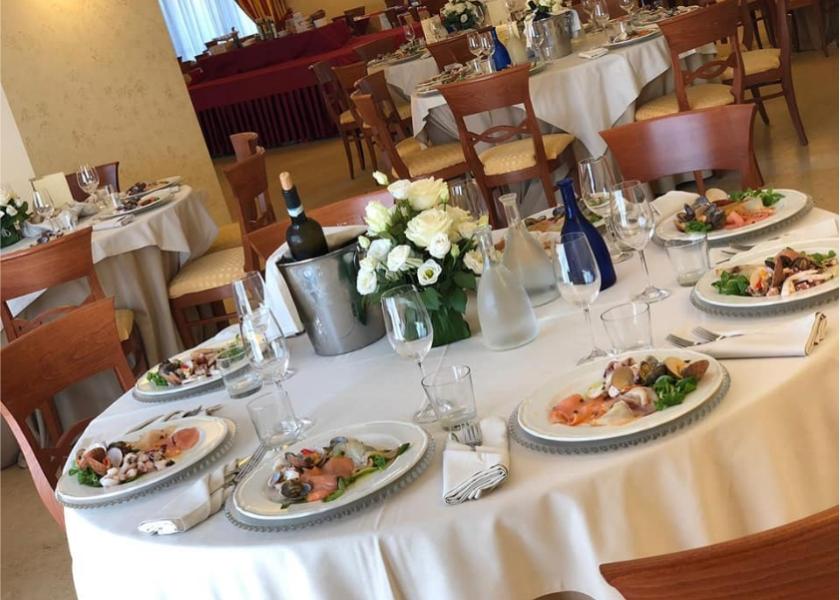 Tavola elegante con piatti di antipasti, fiori bianchi e bottiglia di vino.