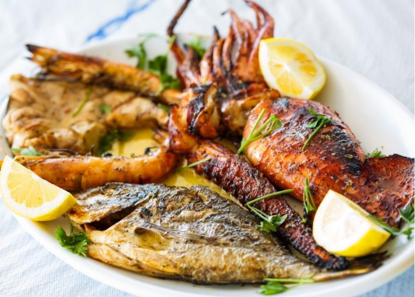 Piatto di pesce grigliato con gamberi, calamari, limone e prezzemolo.